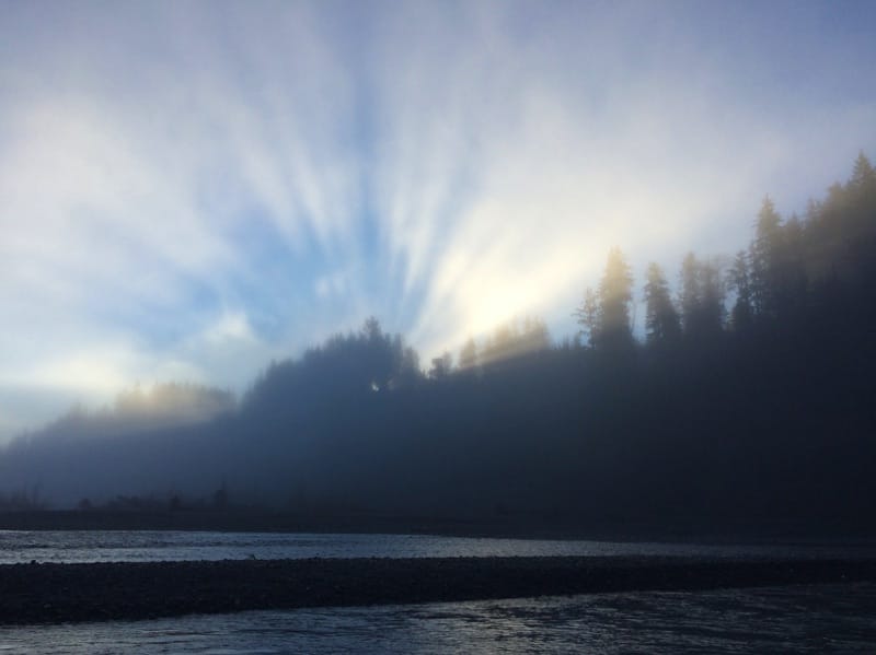 sun bursting through clouds over sea stacks on washington coastal beach